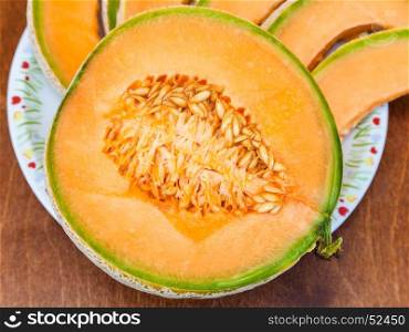 half of ripe sicilian muskmelon (cantaloupe melon) close up on plateon wooden table