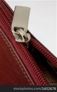 half opened zipper on a red leather bag