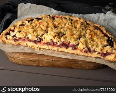 half plum pie crumble on a brown wooden cutting board, close up