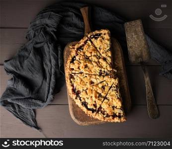 half plum pie crumble on a brown wooden cutting board, top view
