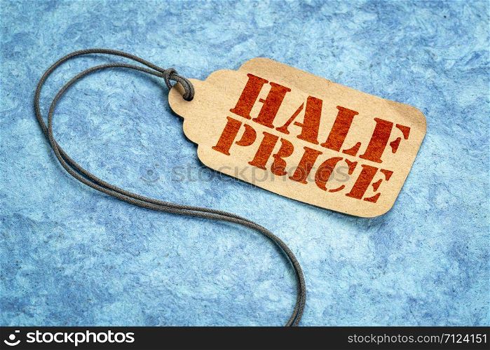 half price sign - a paper price tag with a twine against blue textured paper, shopping marketing concept