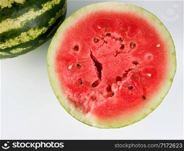 half ripe watermelon with red juicy pulp and seeds and a whole green on a white background, sweet summer berry, top view