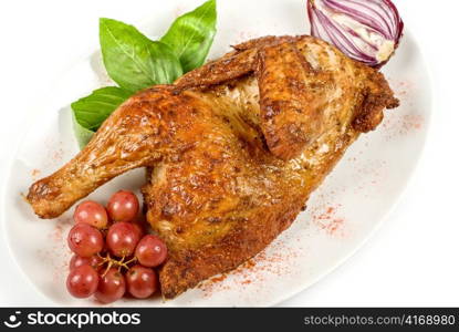 Half roasted chicken closeup with grape and greens on a white