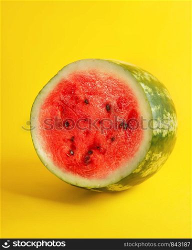 half round ripe red watermelon with brown seeds on a yellow background, summer berry