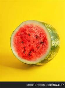 half round ripe red watermelon with brown seeds on a yellow background, summer berry