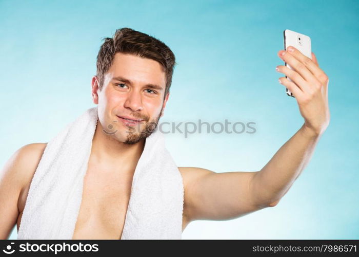 Half shaved man taking selfie self photo.. Young man with half shaved face beard hair taking selfie self photo with smartphone camera. Handsome guy on blue. Skin care and hygiene.