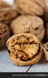 Half walnut kernel and whole walnuts on a wooden background closeup