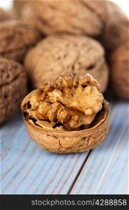 Half walnut kernel and whole walnuts on a wooden background closeup