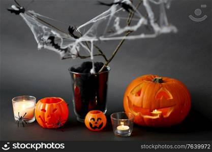 halloween and holiday concept - jack-o-lantern or carved pumpkin, burning candles and spider web decoration. pumpkins, candles and halloween decorations