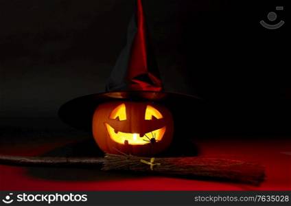 halloween and holiday decorations concept - jack-o-lantern in witch&rsquo;s hat with spider and broom in darkness. halloween jack-o-lantern in witch&rsquo;s hat and broom