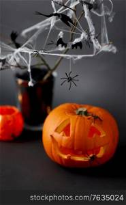 halloween and holiday decorations concept - jack-o-lantern or carved pumpkin, spiders and bats on spiderweb. pumpkins, candles and halloween decorations