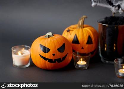 halloween and holiday decorations concept - jack-o-lanterns or carved pumpkins and burning candles. pumpkins, candles and halloween decorations