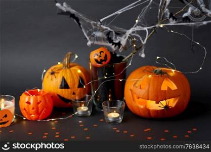 halloween and holiday decorationsconcept - jack-o-lantern or carved pumpkin, burning candles, electric garland string, spiders and bats on spiderweb. pumpkins, candles and halloween decorations