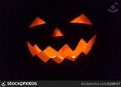 halloween and holidays concept - spooky jack-o-lantern or carved pumpkin lantern burning in darkness. halloween jack-o-lantern burning in darkness