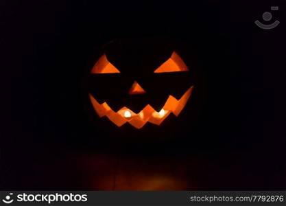 halloween and holidays concept - spooky jack-o-lantern or carved pumpkin lantern burning in darkness. halloween jack-o-lantern burning in darkness