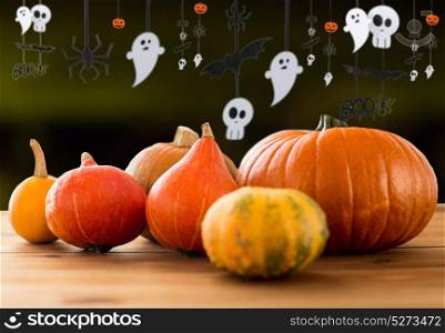 halloween and holidays - pumpkins on wooden table and paper party decorations over dark background. pumpkins and halloween party garland