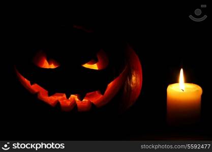 Halloween carved pumpkin and candle on black background