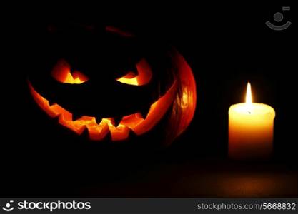 Halloween carved pumpkin and candle on black background
