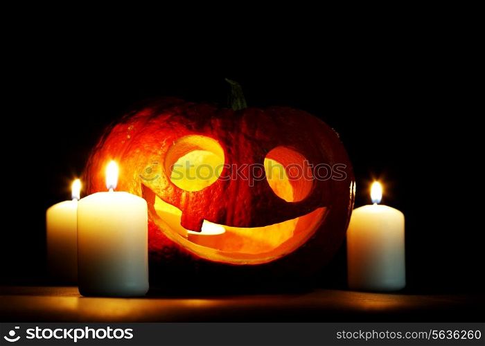 Halloween carved pumpkin and candles on black background