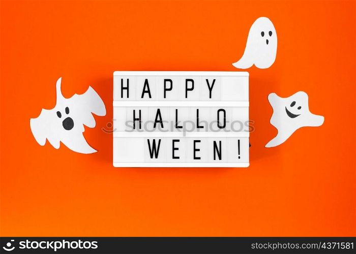 Halloween concept. Festive decorations - paper ghosts and spider web on an orange background.. Halloween concept. Festive decorations - paper ghosts and spider web on orange background.