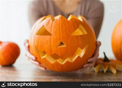 halloween, decoration and holidays concept - close up of woman with carved pumpkin or jack-o-lantern at home. close up of woman with halloween pumpkin at home