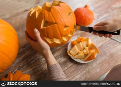 halloween, decoration and holidays concept - close up of woman with knife carving pumpkin or jack-o-lantern at home. close up of woman carving halloween pumpkin