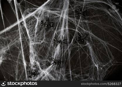 halloween, decoration and horror concept - black toy spiders on artificial cobweb. halloween decoration of black toy spiders on web
