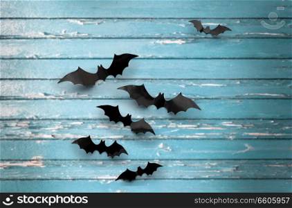 halloween, decoration and scary concept - black bats flying over blue shabby boards background. black bats over blue shabby boards background