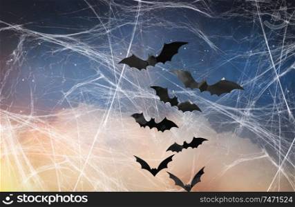 halloween, decoration and scary concept - black bats flying over starry night sky and spiderweb background. black bats over starry night sky and spiderweb