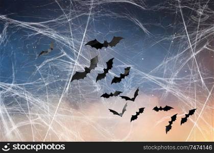 halloween, decoration and scary concept - black bats flying over starry night sky and spiderweb background. black bats over starry night sky and spiderweb