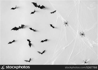 halloween, decoration and scary concept - black flying bats and spiders on web over white background. halloween decoration of bats and spiders on web