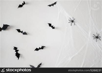 halloween, decoration and scary concept - black flying bats and spiders on web over white background. halloween decoration of bats and spiders on web