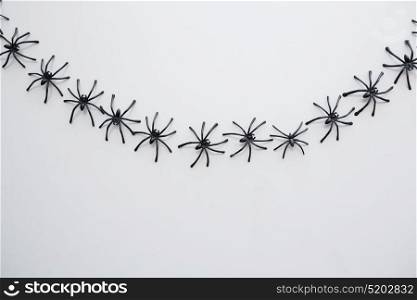 halloween, decoration and scary concept - black toy spiders chain over white background. black toy spiders chain over white background