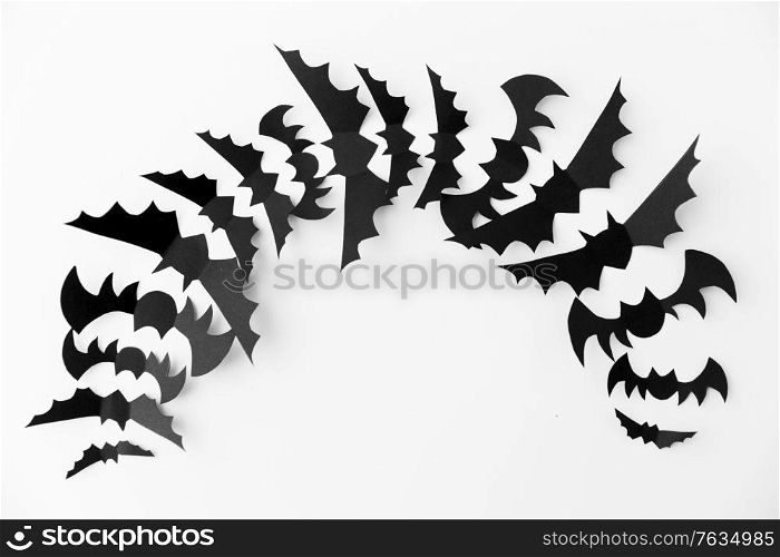 halloween, decoration and scary concept - flock of black paper bats flying over white background. flock of black paper bats over white background
