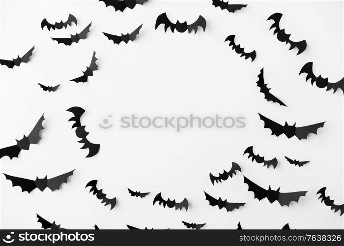halloween, decoration and scary concept - flock of black paper bats flying over white background. flock of black paper bats over white background