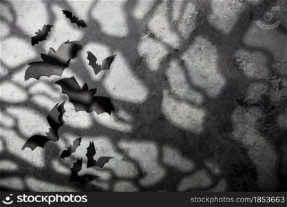 Halloween decoration concept - black paper bats, moonlight and scary trees shadows background