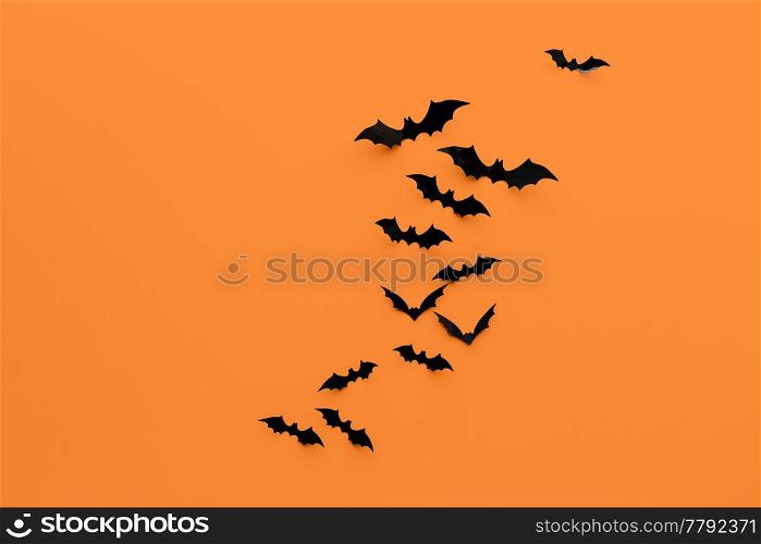 halloween decorations concept - many black paper bats on orange background. black halloween bats on orange background
