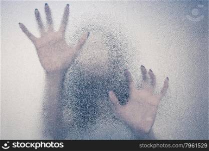 Halloween female hand behind transparent glass background as silhouette