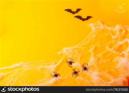 Halloween flat lay banner scene on orange background with bats and spiders in web. Halloween scene on orange background