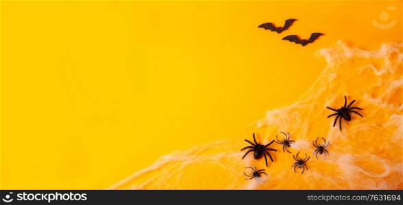 Halloween flat lay banner scene on orange background with spiders in web. Halloween scene on orange background