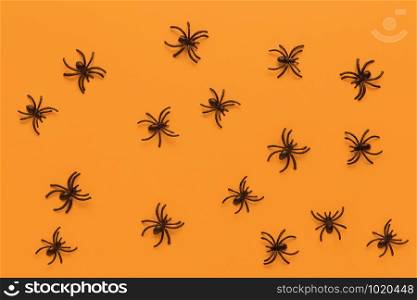 Halloween flat lay. Pattern from black spiders on orange background. Minimal style. Horizontal. Trick-or-treat concept.