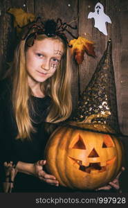 Halloween - girl in a suit with a pattern on her face and with a pumpkin