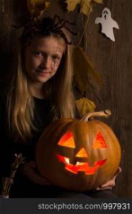 Halloween - girl in a suit with a pattern on her face and with a pumpkin