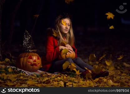 Halloween - girl in a suit with a pattern pumpkin lantern with eyes and pumpkin at the garden