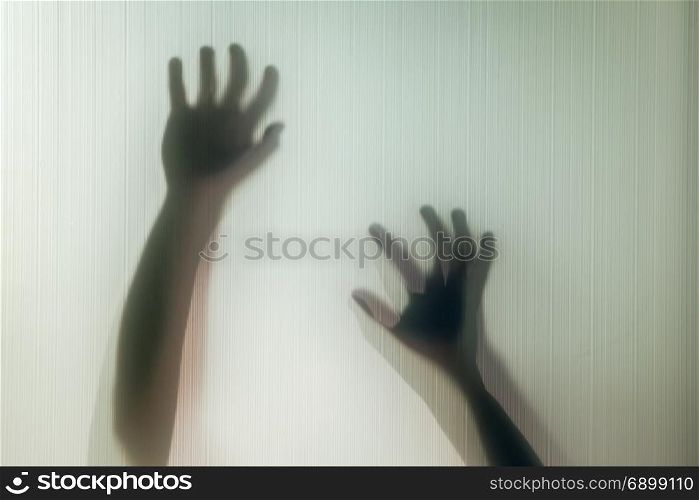 Halloween hands behind transparent glass background as silhouette
