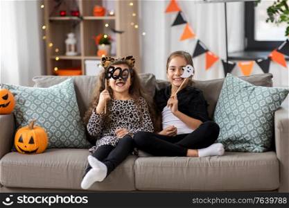 halloween, holiday and childhood concept - smiling little girls in costumes with jack-o-lantern pumpkins at home. girls in halloween costumes with pumpkins at home