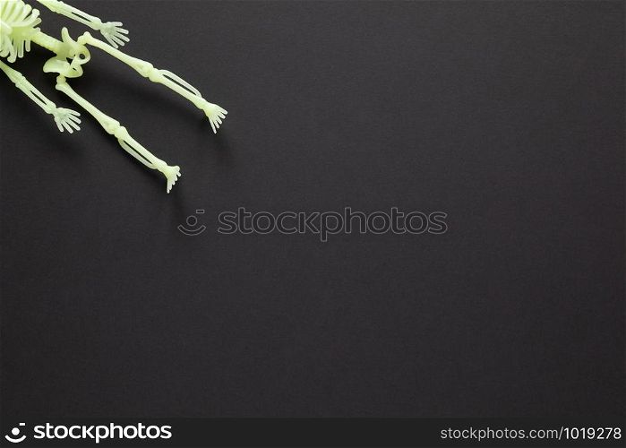 Halloween holiday flat lay. White fluorescent skeleton on black background with copy space. Minimal style. Horizontal. Trick-or-treat concept.