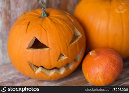 halloween, holidays and decoration concept - jack-o-lantern or carved pumpkin on wooden table at home. jack-o-lantern or carved halloween pumpkin