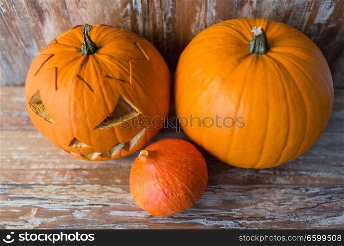 halloween, holidays and decoration concept - jack-o-lantern or carved pumpkin on wooden table at home. jack-o-lantern or carved halloween pumpkin
