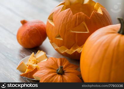 halloween, holidays and decoration concept - jack-o-lantern or carved pumpkin on wooden table at home. jack-o-lantern or carved halloween pumpkin